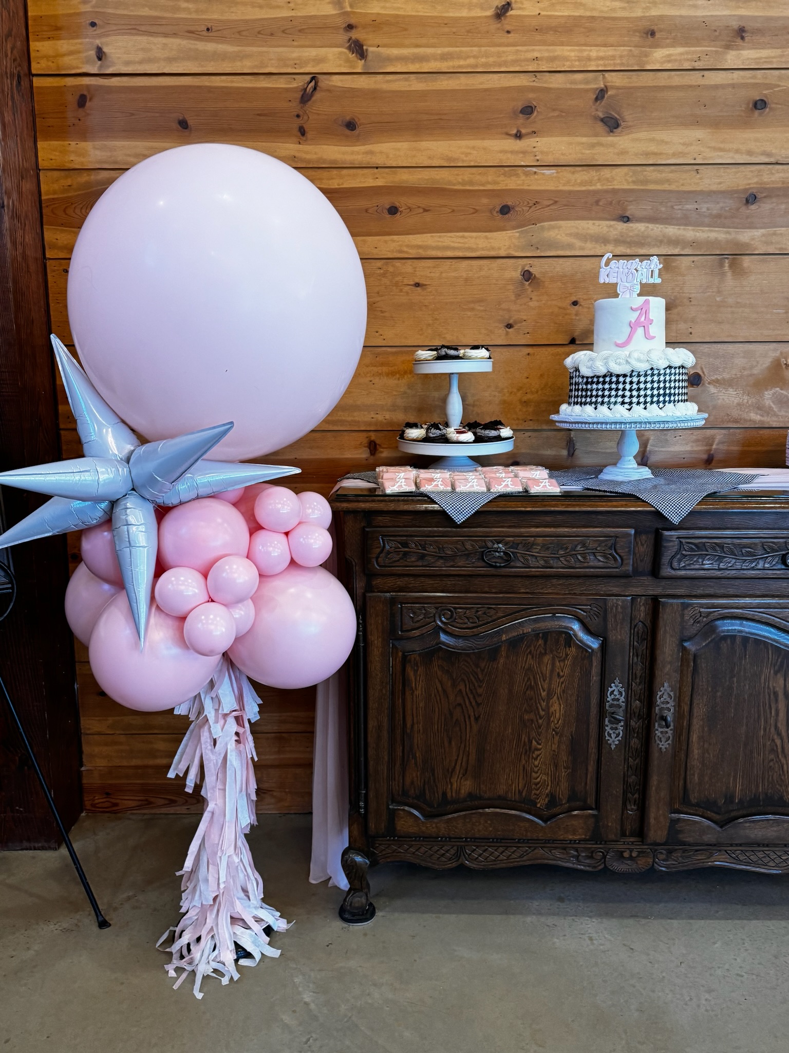 Small balloon cluster with matching black, white, and pink cakes and cupcakes.