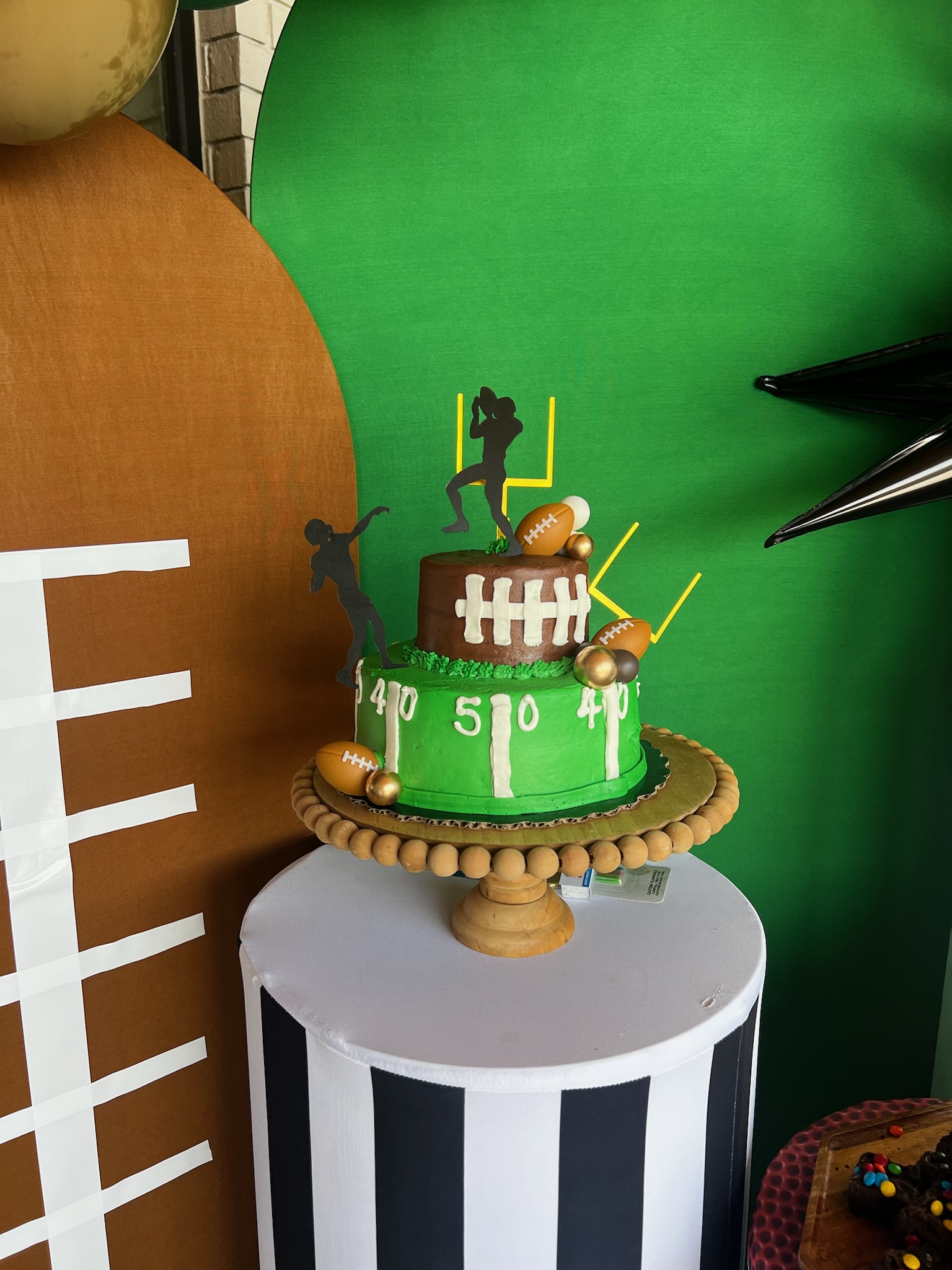 football birthday bash set up, arched wood backdrops, sports-themed backdrops, football-themed cake, football cake toppers, sports-themed cylinder plinth covers